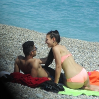 Brunette girl on the beach with her boyfriend in a peach bikini Brunette girl in peach bikini