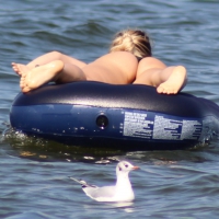 Black thong bikini blonde with a nice ass out on a tube in the water Black thong bikini blonde