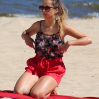 Hottie undressing from her red shorts to her bikini to layout on the beach Hottie undressing on the beach to tan