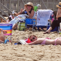 Girl laying on the beach reading a book in a pink bikini (busted) Girl reading in pink bikini