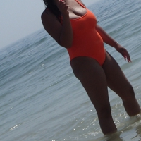 Beach girl with big boobs in an orange swimsuit Beach girl in orange swimsuit