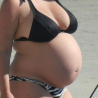 Pregnant girl in bikini on the beach with pokies Pregnant girl on the beach