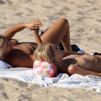 Topless mom and daughter on the beach getting some sun Topless mom and daughter