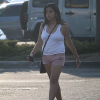 Cute girl, possibly Latina, walking through the parking lot in shorts Cute girl walking in the parking lot in shorts