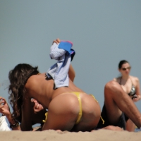 Topless lady on the beach in a gold thong with a nice ass Topless lady in gold thong